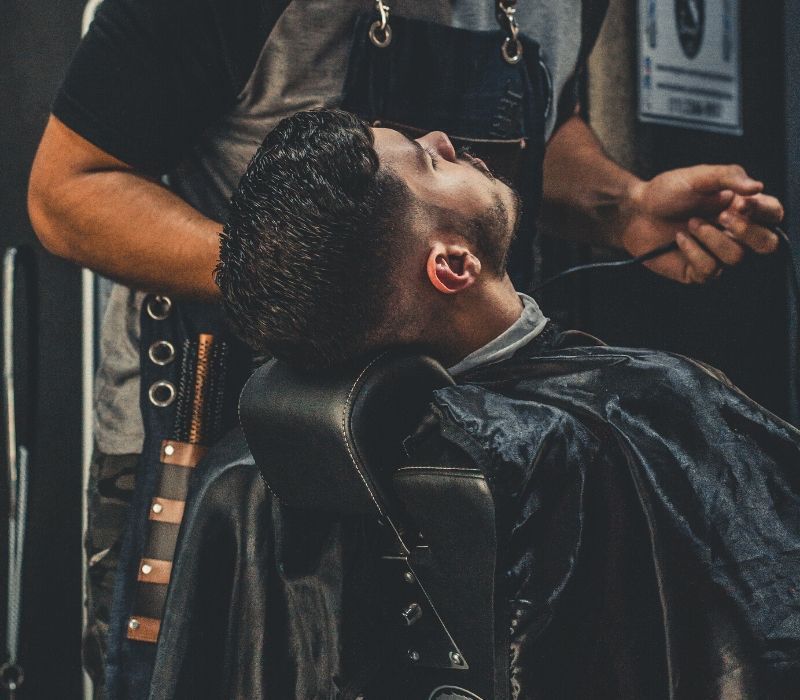 A man in a barber's chair while getting his hair coloured in Fort Lauderdale and Coral Gables.